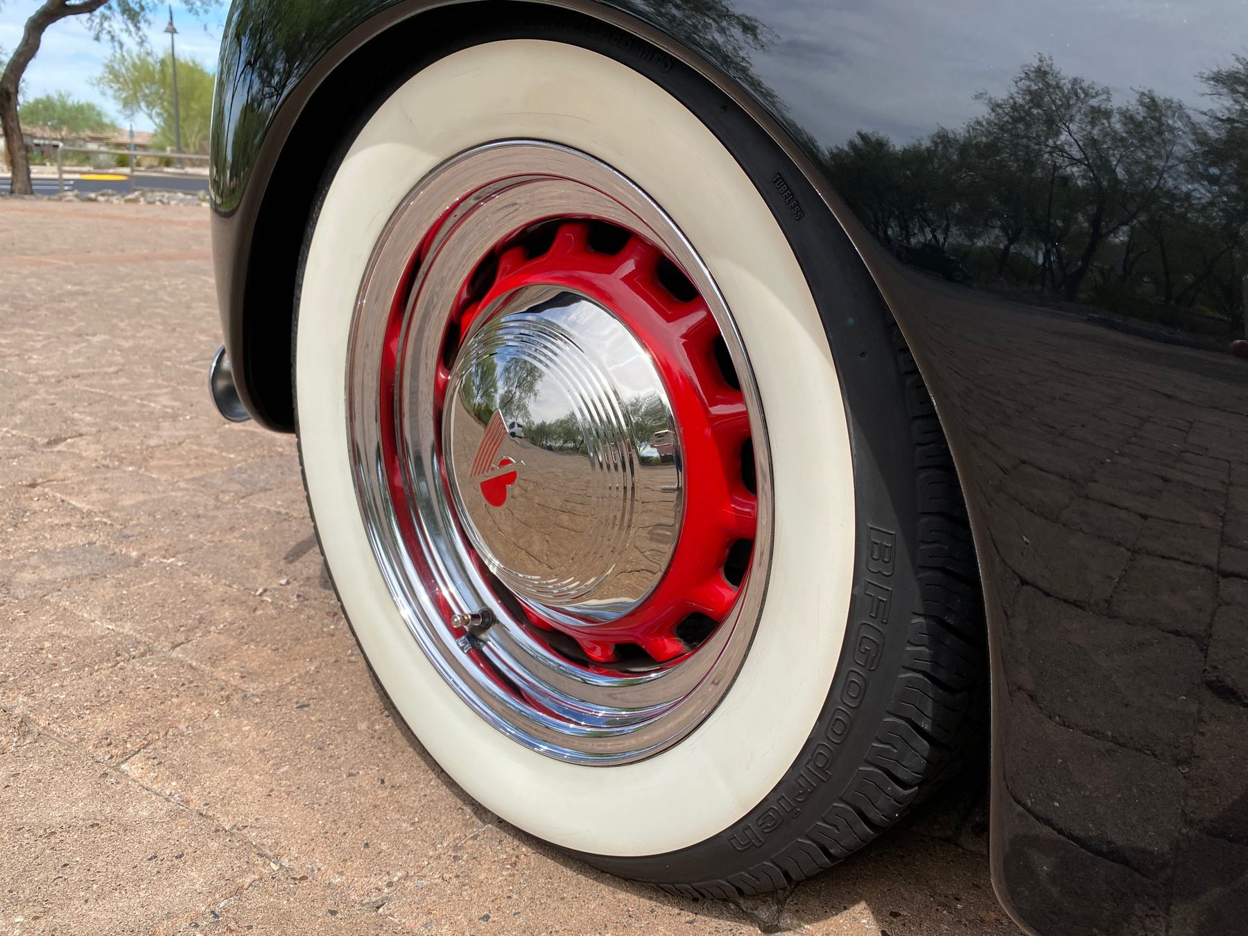 Red-painted wheel with chrome trim ring and whitewall tire